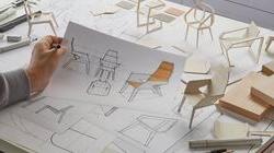 Designer working on product plan draft for chair with pencil in hand